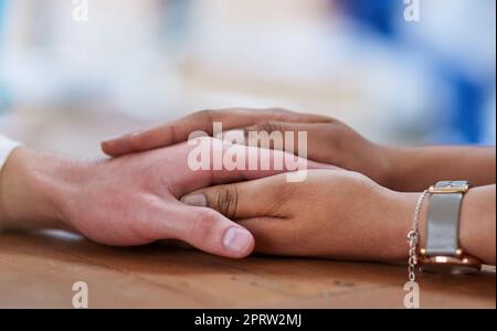 Ich gehe nirgendwohin. Zwei Personen, die bequem Händchen halten Stockfoto