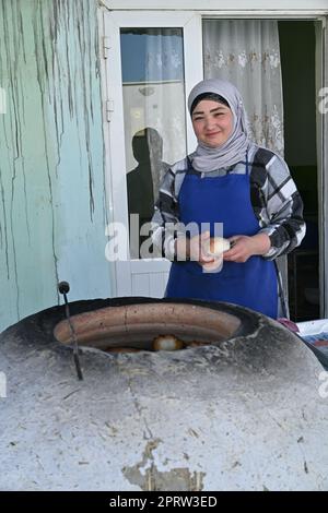 Eine usbekische Frau, die in einem Tandir-Ofen in Bukhara, Usbekistan, Somsa, einen traditionellen lokalen Snack, kocht Stockfoto