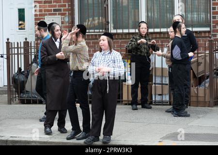 Jeschiwa-Schüler hängen alleine und in Gruppen während der Pause ab. Außerhalb einer Schule in Brooklyn, New York. Stockfoto