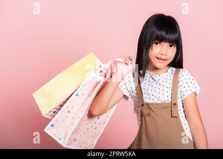 Asiatisches kleines Kind 10 Jahre alt lächelnd mit bunten Einkaufstaschen in den Händen Stockfoto