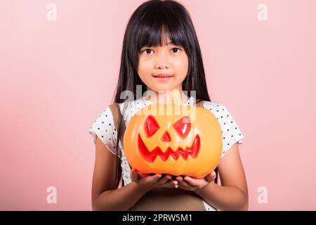 Asiatisches kleines Kind 10 Jahre alt hält geschnitzten Halloween Kürbis Stockfoto