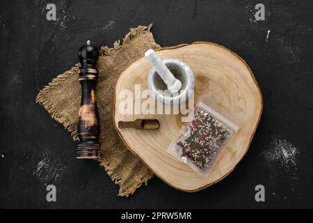 Holzquerschnitt mit Gemisch aus Paprika in Kunststoffverpackung, Mörtel und Mühle Stockfoto