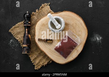 Holzquerschnitt mit Sumac in Kunststoffverpackung, Mörtel und Mühle Stockfoto