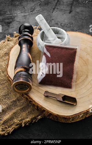 Holzquerschnitt mit Sumac in Kunststoffverpackung, Mörtel und Mühle Stockfoto