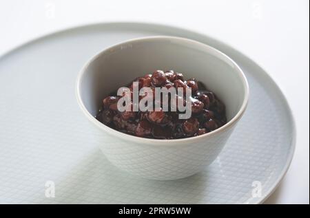 Gekochte Azuki-Bohnen auf weißem Hintergrund. Stockfoto