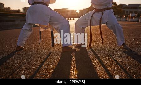 Bereit für den Kampf. Zwei Sportler stehen sich gegenüber und üben ihr Karate, während sie GI tragen. Stockfoto