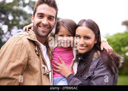 Liebe macht eine Familie. Ein beschnittenes Porträt von zwei glücklichen Eltern mit ihrer jungen Tochter, die im Freien steht. Stockfoto