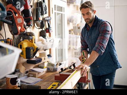 Visionen von Erfolg aus Holz. Porträt eines hübschen jungen Handwerkers, der vor seinen Arbeitswerkzeugen steht. Stockfoto