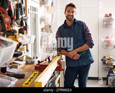 Träume werden in meine Werkstatt geboren. Porträt eines hübschen jungen Handwerkers, der vor seinen Arbeitswerkzeugen steht. Stockfoto