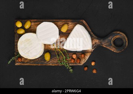 Übersichtsansicht des Sortiments an Brie und Camembert Käse auf Holzschneidplatte. Stockfoto