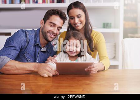 Es ist ein wunderbares Lehrmittel. Junge Eltern zeigen ihrer kleinen Tochter, wie man eine Tablette verwendet. Stockfoto