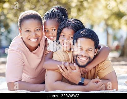 Die afrikanische Familie lächelt im Park, hat Spaß in der Sommersonne und genießt die Natur im Urlaub. Schwarzer afrikanischer Mann, lächelnde Frau und Kinder. Kinder umarmen Dad, um sich mit Eltern im Garten zu verbinden Stockfoto