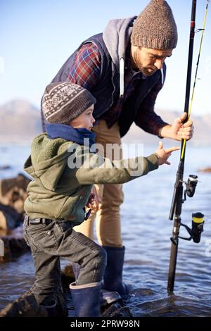 Was hast du gesehen. Ein süßer kleiner Junge, der mit seinem Vater am Meer fischt. Stockfoto