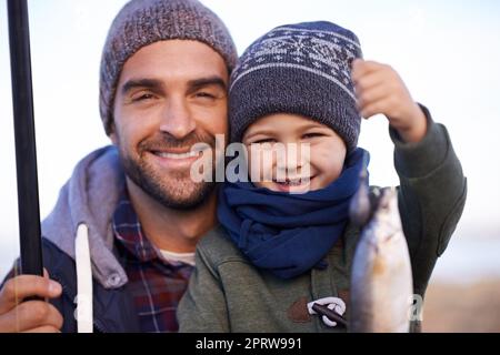 Schauen Sie, was wir gefangen haben. Porträt eines liebevollen Vaters und Sohnes mit den Fischen, die sie zusammen gefangen haben. Stockfoto