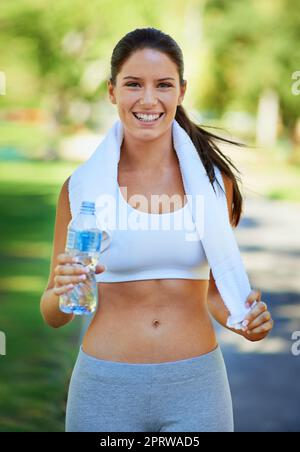 Nach H2O:00 Uhr ist es soweit. Eine Frau hält nach dem Training eine Flasche Wasser in der Hand. Stockfoto