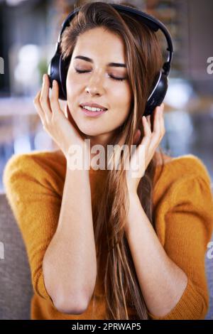 Es ist eine dieser entspannten Wiedergabelisten. Schöne junge Frau, die zu Hause Musik hört. Stockfoto