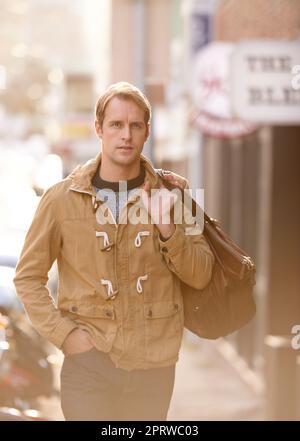 Ein modischer Mann, der durch die Stadt läuft. Stockfoto