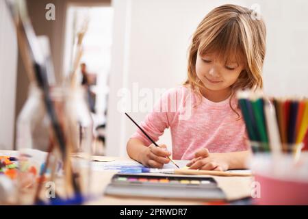 Diese für Mama. Ein lächelndes kleines Mädchen, das in der Schule Kunst und Handwerk macht. Stockfoto