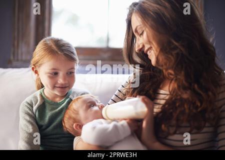 Sie liebt ihre kleine Schwester. Eine Aufnahme einer Familie, die Zeit miteinander verbringt, während Mama das Baby pflegt. Stockfoto