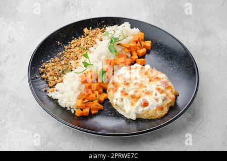 Gehacktes Schweinefleisch, gebacken mit Schinken und Käse, serviert mit Karotten und Reis Stockfoto