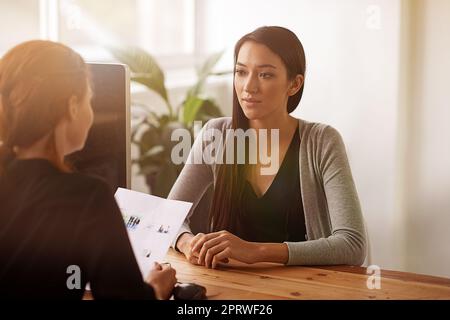 Interview in Arbeit. Zwei junge Geschäftsfrauen diskutieren an einem Schreibtisch. Stockfoto