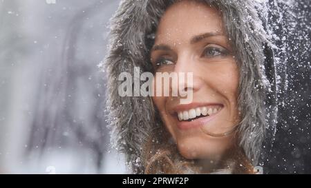 Liebe den ersten Schneefall. Eine attraktive Frau, die sich draußen im Schnee genießt. Stockfoto