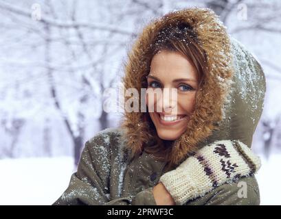 Liebe den ersten Schneefall. Eine attraktive Frau, die sich draußen im Schnee genießt. Stockfoto