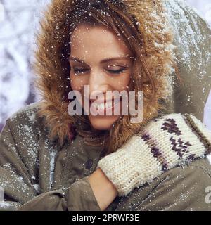 Liebe den ersten Schneefall. Eine attraktive Frau, die sich draußen im Schnee genießt. Stockfoto