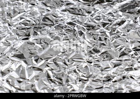 Nahaufnahme: Zerknitterte silberfarbene, glänzende Aluminiumfolie. Stockfoto