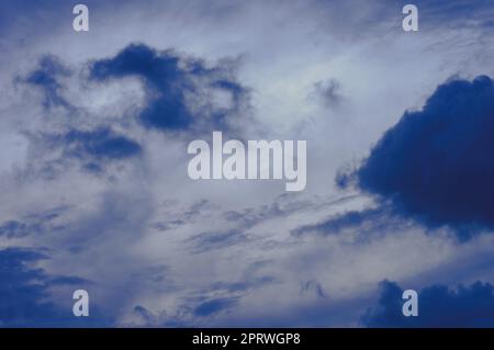 Dunkle Wolken im Hintergrund des blauen Himmels. Dunkle Regenwolken, die am Himmel bei Sonnenuntergang schwimmen. Natur Hintergrund. Stockfoto