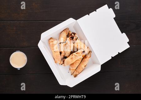 In Teig gerollte Birnenscheiben mit Karamellsauce im Paket zum Mitnehmen Stockfoto