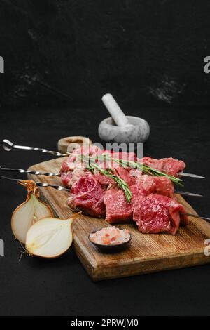 Spieße mit rohem Rindfleisch auf Holzbrett Stockfoto