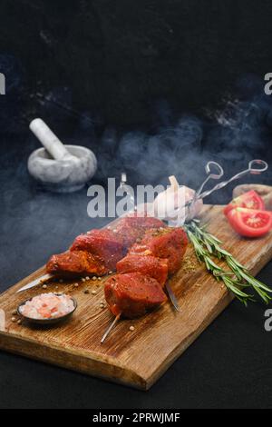 Räucherspieße mit mariniertem rohem Schweinefleisch auf dem Schneidebrett Stockfoto