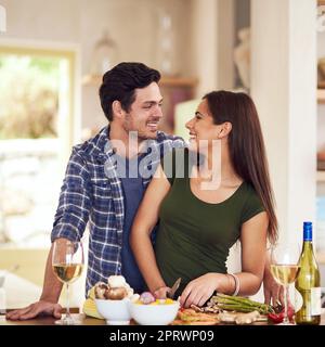 Was kocht, sieht gut aus. Ein junges Paar, das zusammen in der Küche zu Hause das Abendessen zubereitete Stockfoto