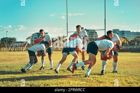 Arbeiten an der Verbesserung ihrer Tackling-Fähigkeiten. Eine Gruppe von Rugby-Spielern, die mit Tackle Bags auf dem Feld trainieren. Stockfoto