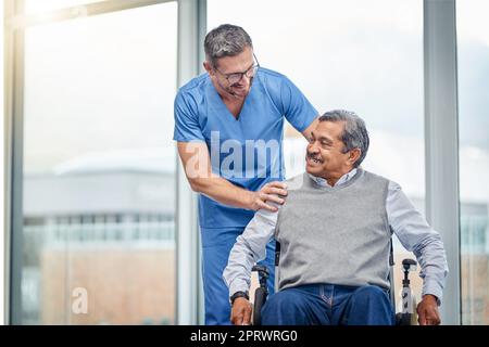 Eine Krankenschwester, die einem älteren Mann im Rollstuhl hilft. Stockfoto