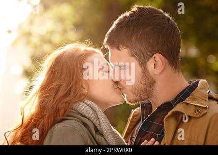 Es gibt keine Liebe ganz wie Ihre erste. Ein glückliches junges Paar einen Kuss im Freien teilen. Stockfoto