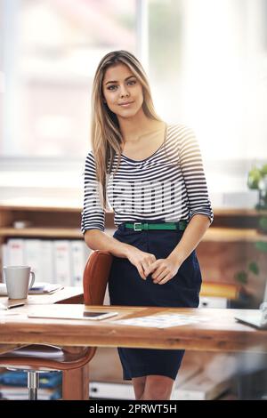 Bitte kommen Sie herein und nehmen Sie Platz. Ein Porträt einer jungen Geschäftsfrau, die hinter ihrem Schreibtisch im Büro steht. Stockfoto