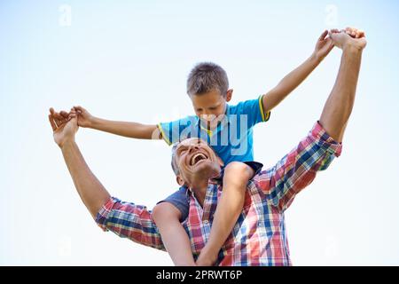 Stolz und Freude des Vatis. Eine Aufnahme eines glücklichen Vaters, der seinen jungen Sohn auf den Schultern trägt. Stockfoto