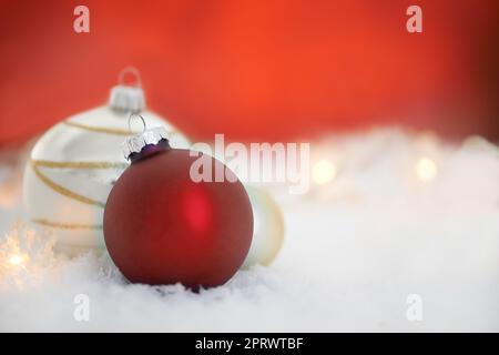 Wir wünschen Ihnen ein schönes Weihnachtsfest. Zwei weihnachtskugeln liegen auf einem Schneebett. Stockfoto