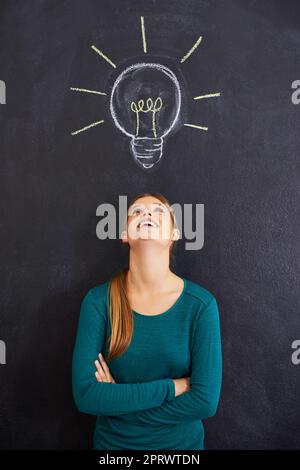 Shes hatte gerade einen Moment der Glühbirne. Eine attraktive junge Frau, die vor einer Tafel stand. Stockfoto