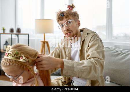 Vater mit verrückter Frisur macht Haare für Tochter Stockfoto