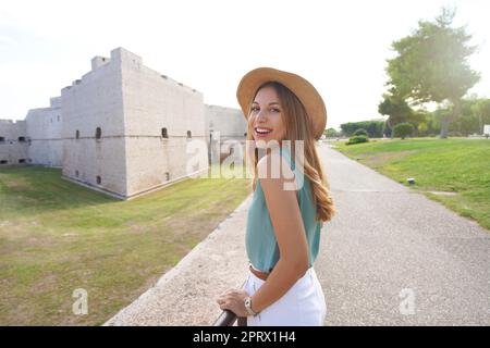 Kulturtourismus in Apulien, Italien. Porträt einer schönen jungen Frau mit Schloss Barletta im Hintergrund, Apulien, Italien. Stockfoto