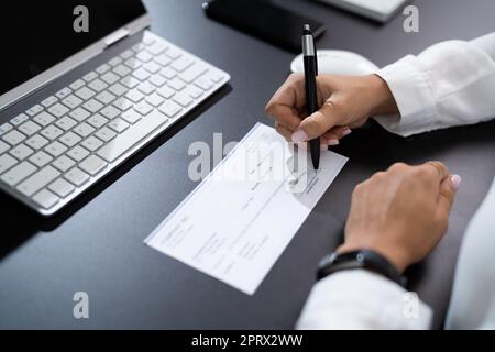 Frau Unterschreibt Bankscheck Stockfoto