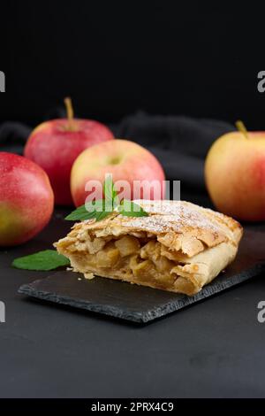 Gebackener Strudel mit Äpfeln, mit Puderzucker bestreut, auf einem schwarzen Brett Stockfoto