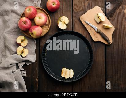 Leeres rundes, antihaftbeschichtetes Backblech, frische Äpfel auf einem braunen Holztisch Stockfoto