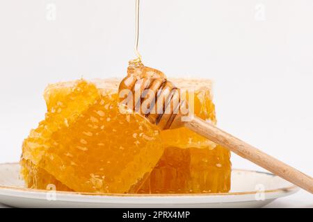 Frisch geschnittener Kammhonig und Holzstiel auf Weiß Stockfoto