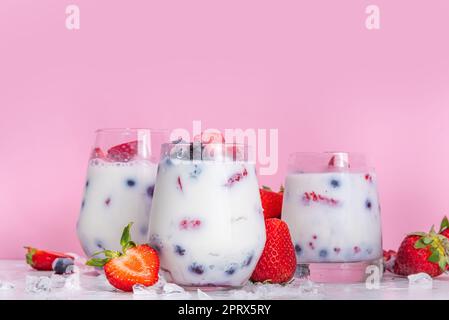 Sommermilchbeere alkoholfreier Cocktail, süße vegane Kokosmilch milchfreier Mocktail, mit frischen Erdbeeren, Heidelbeeren, Himbeeren und zerstoßenem Eis, auf B. Stockfoto