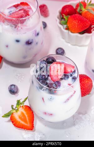 Sommermilchbeere alkoholfreier Cocktail, süße vegane Kokosmilch milchfreier Mocktail, mit frischen Erdbeeren, Heidelbeeren, Himbeeren und zerstoßenem Eis, auf B. Stockfoto