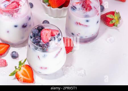 Sommermilchbeere alkoholfreier Cocktail, süße vegane Kokosmilch milchfreier Mocktail, mit frischen Erdbeeren, Heidelbeeren, Himbeeren und zerstoßenem Eis, auf B. Stockfoto
